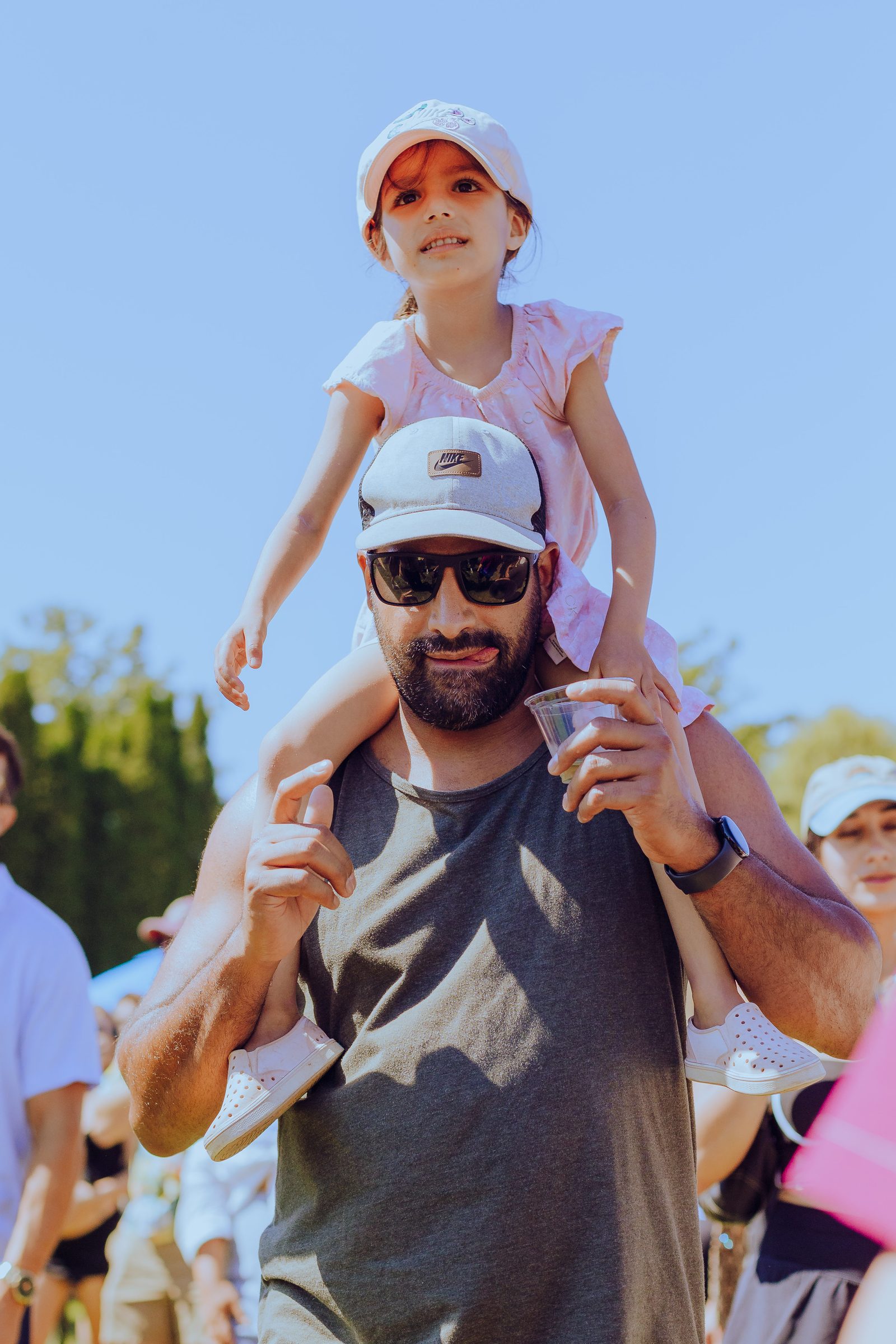 A dad with a little girl on his shoulders in the sunshine