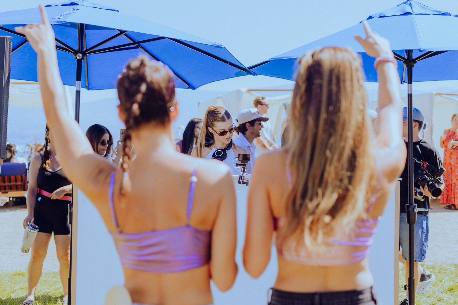 Two friends dancing with hands up under blue umbrellas